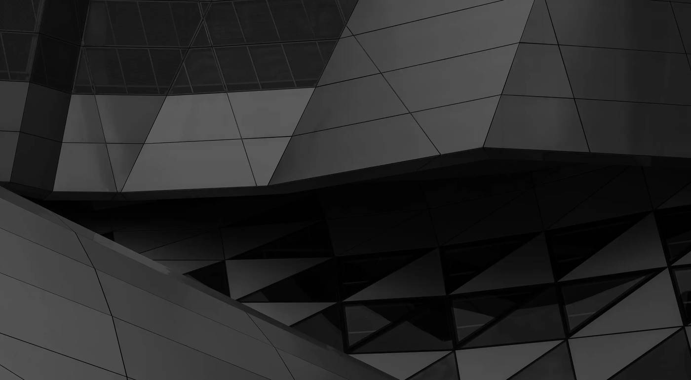 Fachada de panel composite negro de volúmenes angulares, de noche